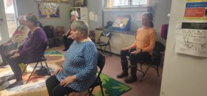 Picture of chair yoga participants at Whiting Library. Patrons are sitting in chairs and stretching their necks.