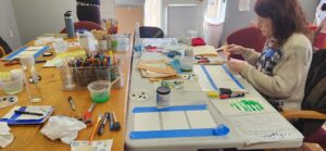 Participants at the Whiting Library Creative Aging Collage Making workshop. The participant is cutting and gluing papers.